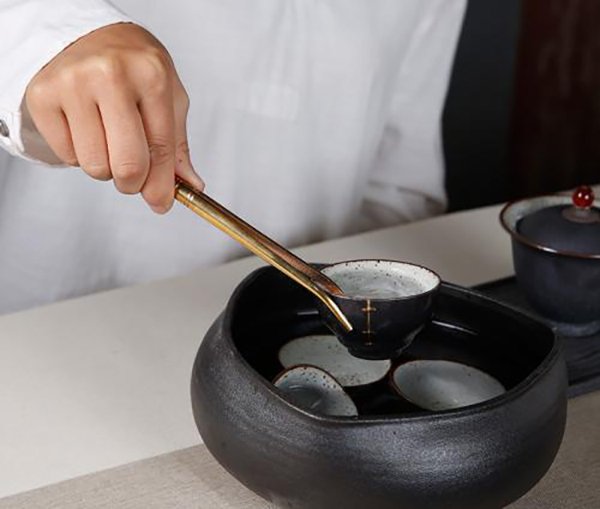 Using a tea tweezer to protect your hands from the hot water 