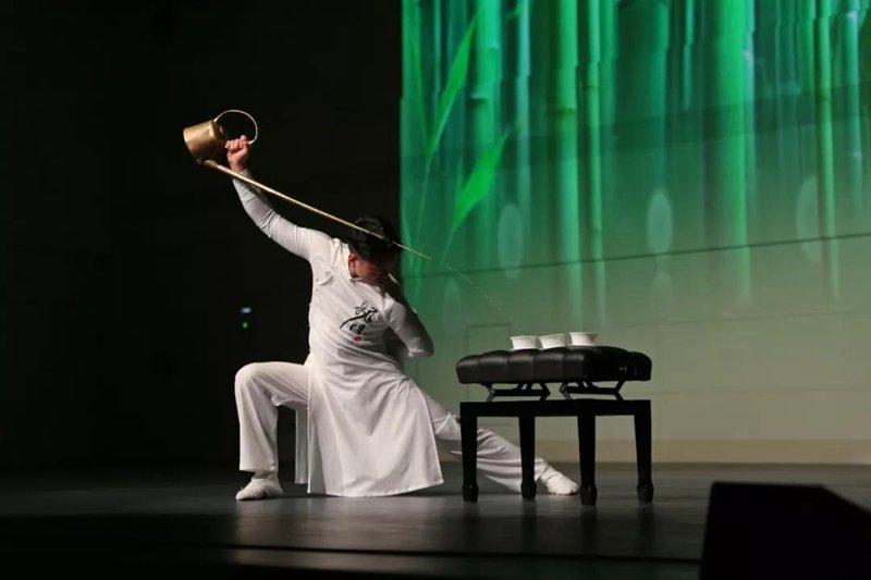 A Dr. Tea is playing a show using a long spout copper teapot