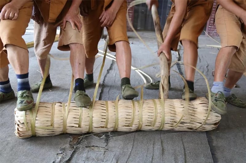 Tea masters treading the bamboo cane container to tight it